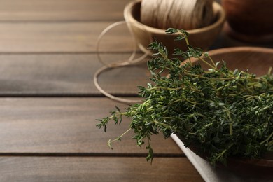 Photo of Bunch of aromatic thyme on wooden table, closeup. Space for text