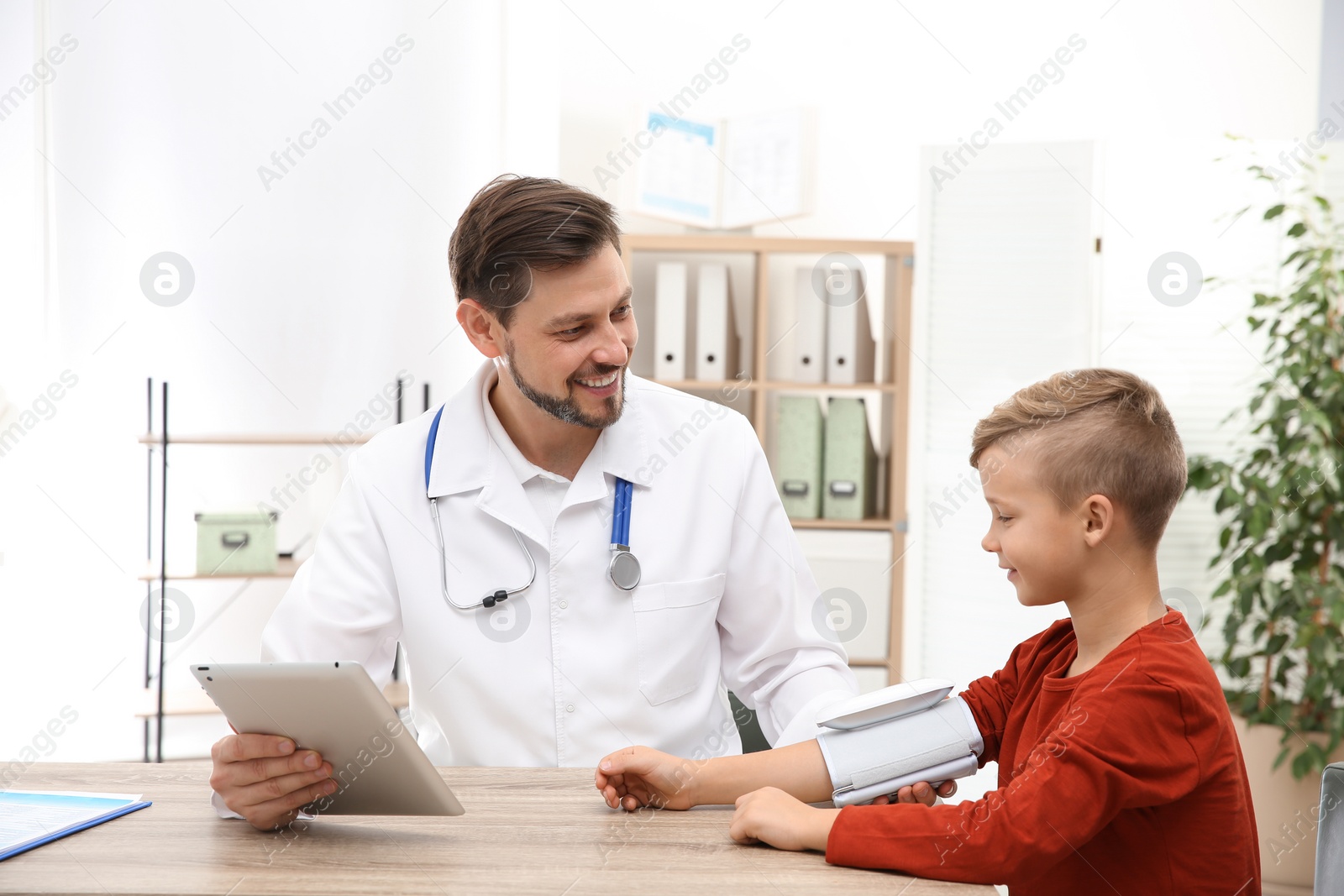 Photo of Doctor checking little boy's pulse with medical device in hospital