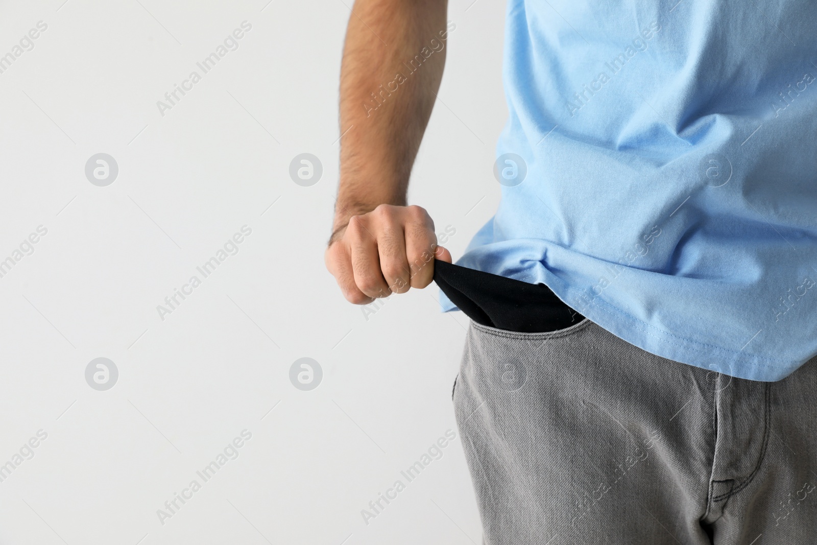 Photo of Man showing empty pocket on light background. Space for text