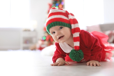 Cute baby in Christmas costume on floor at home