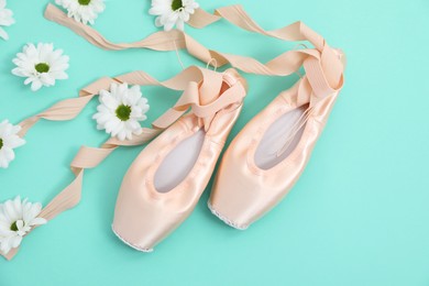 Photo of Ballet shoes. Elegant pointes and flowers on turquoise background, flat lay