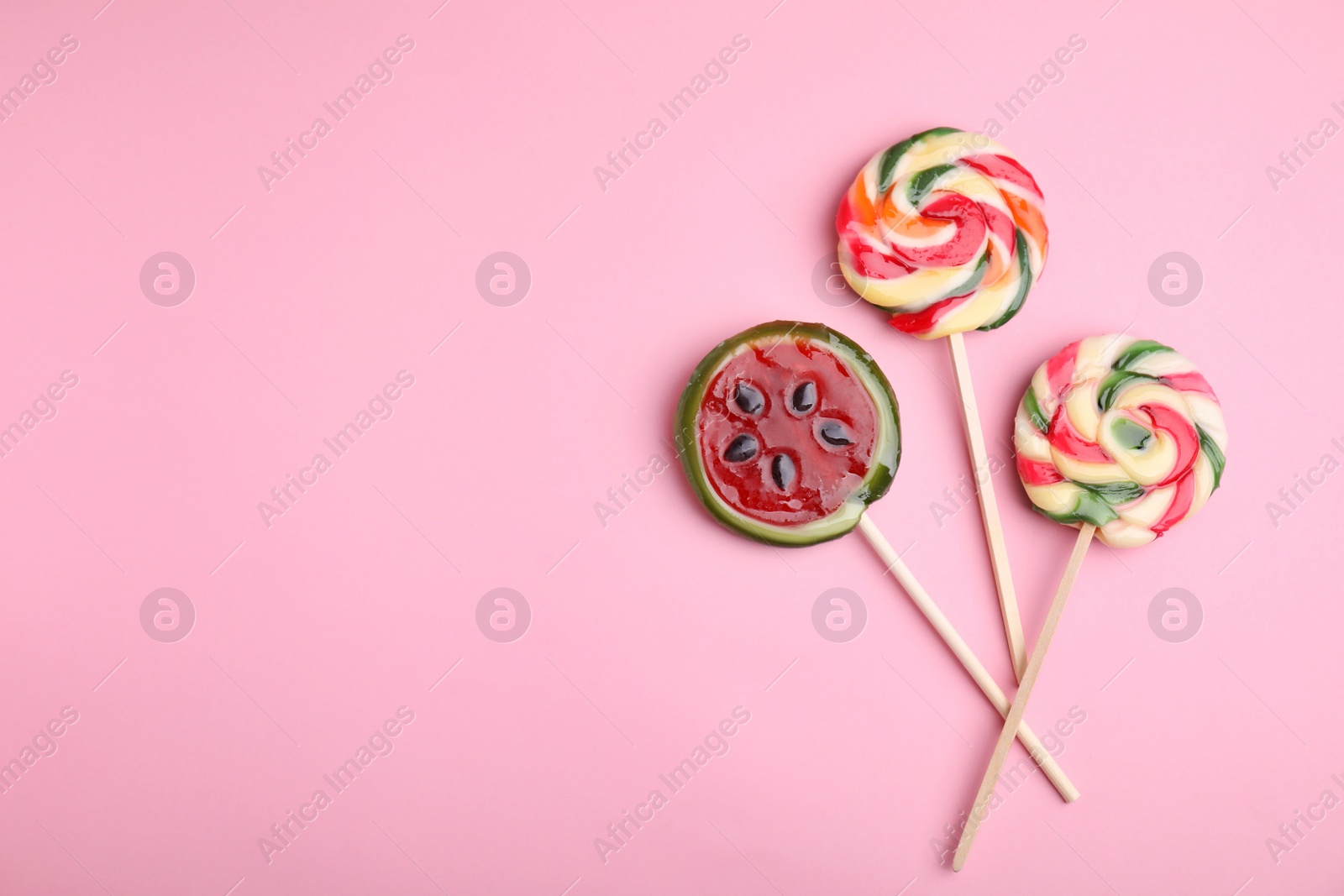 Photo of Different colorful lollipops on pink background, flat lay. Space for text