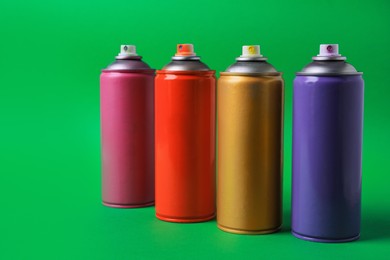 Photo of Cans of different graffiti spray paints on green background