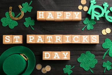 Photo of Words Happy St. Patrick's Day and festive decor on black wooden background, flat lay