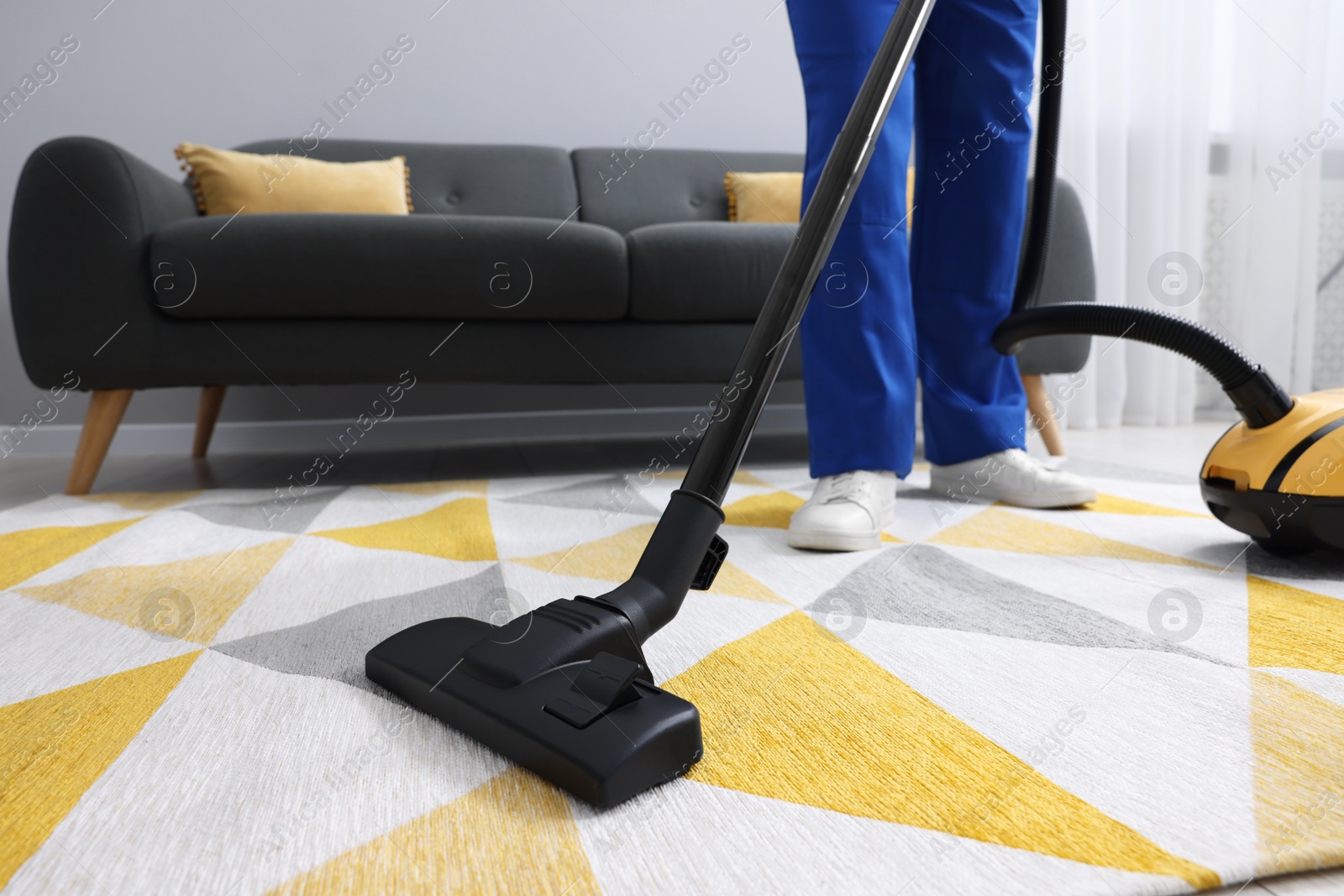 Photo of Dry cleaner's employee hoovering carpet with vacuum cleaner in room, closeup