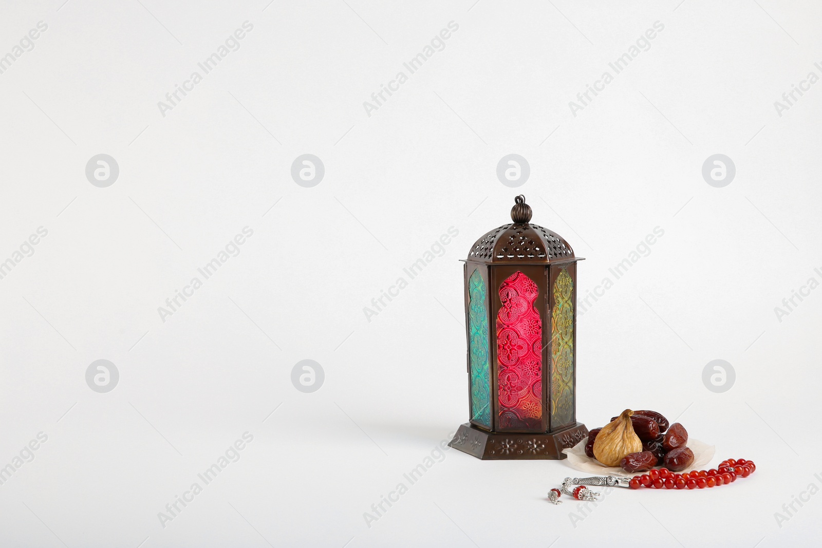 Photo of Muslim lamp, dates and prayer beads on white background. Space for text