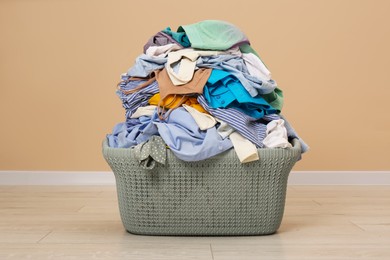 Photo of Laundry basket with clothes near beige wall indoors