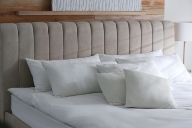 Photo of Bed with soft pillows in room. Modern interior