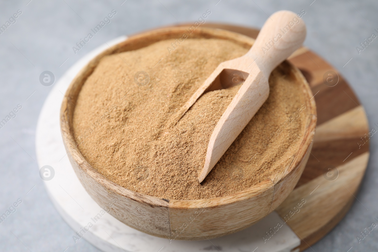 Photo of Dietary fiber. Psyllium husk powder in bowl and scoop on grey table, closeup