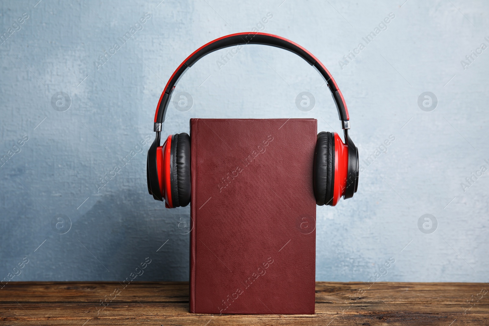 Photo of Book and modern headphones on wooden table