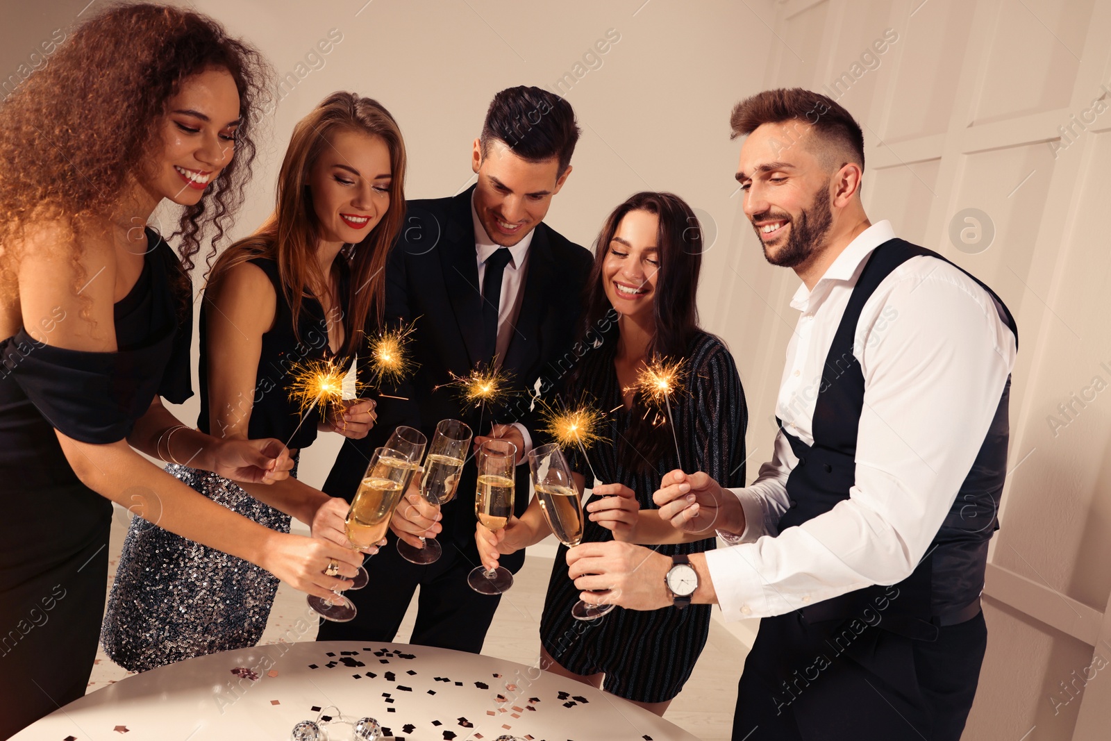 Photo of Happy friends clinking glasses of sparkling wine indoors. New Year celebration