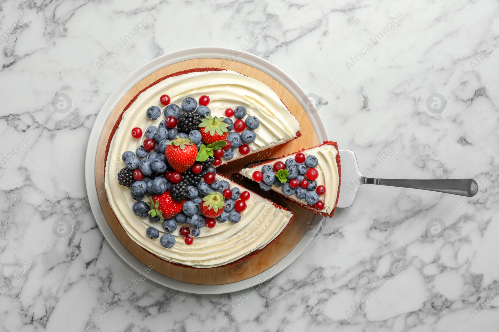 Photo of Delicious homemade red velvet cake with fresh berries on marble table, top view