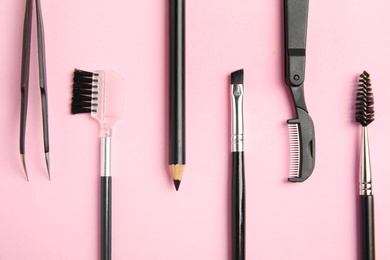 Photo of Set of professional eyebrow tools on pink background, flat lay