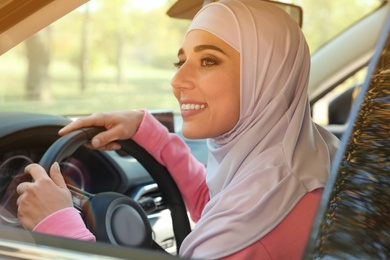 Photo of Modern Muslim woman in hijab driving car