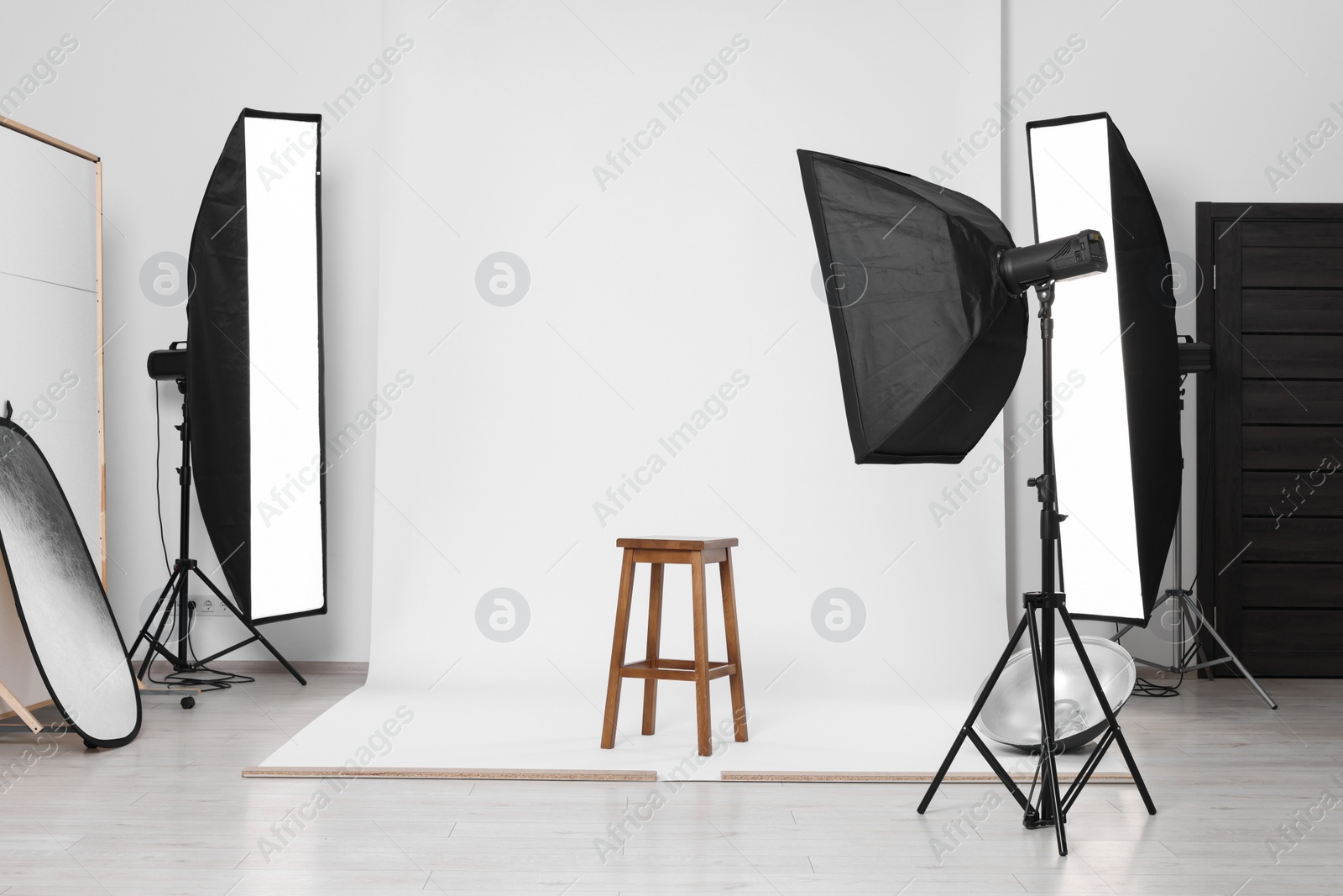 Photo of White photo background, stool and professional lighting equipment in studio