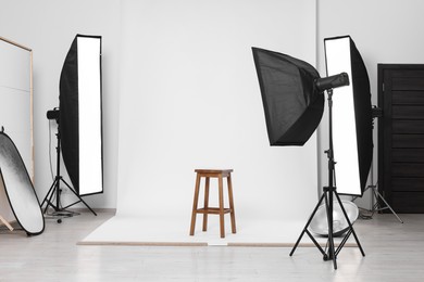 Photo of White photo background, stool and professional lighting equipment in studio