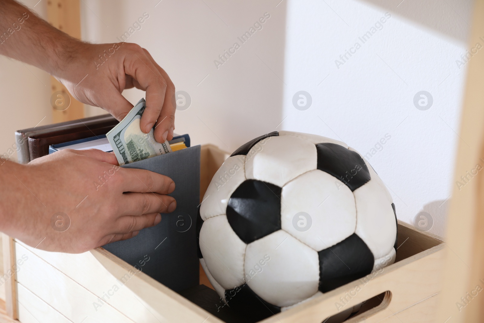 Photo of Man hiding money in book indoors, closeup. Financial savings