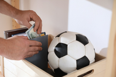 Man hiding money in book indoors, closeup. Financial savings