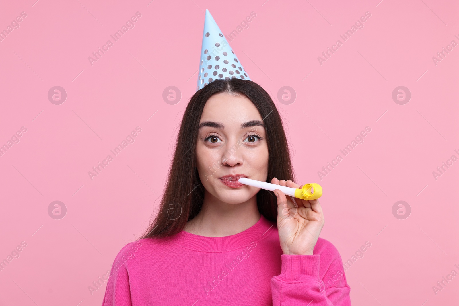 Photo of Woman in party hat with blower on pink background