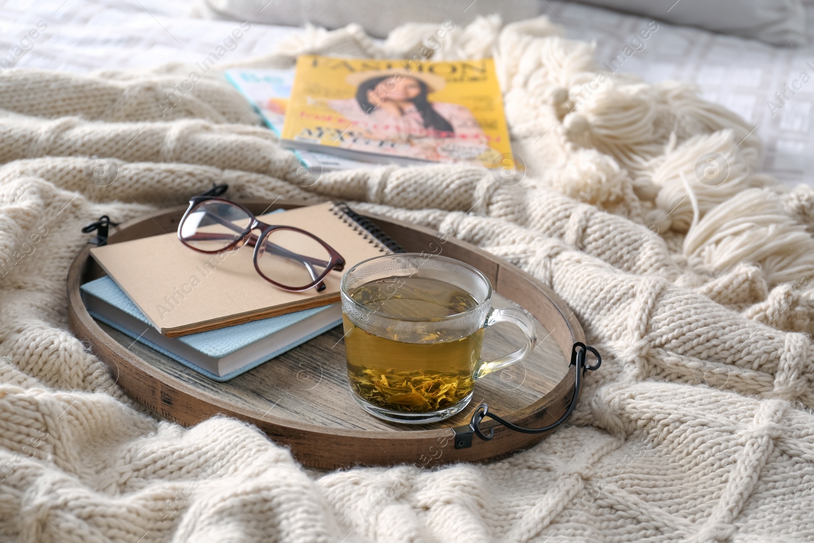 Photo of Stylish tray with different interior elements and tea on bed