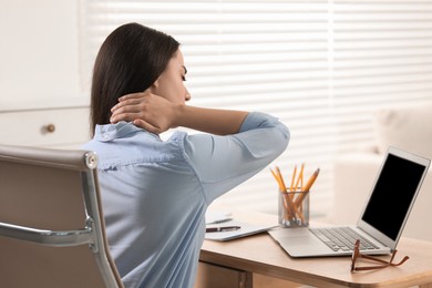 Photo of Woman suffering from neck pain at table in office