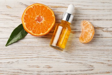 Photo of Bottle of tangerine essential oil and fresh fruit on white wooden table, flat lay