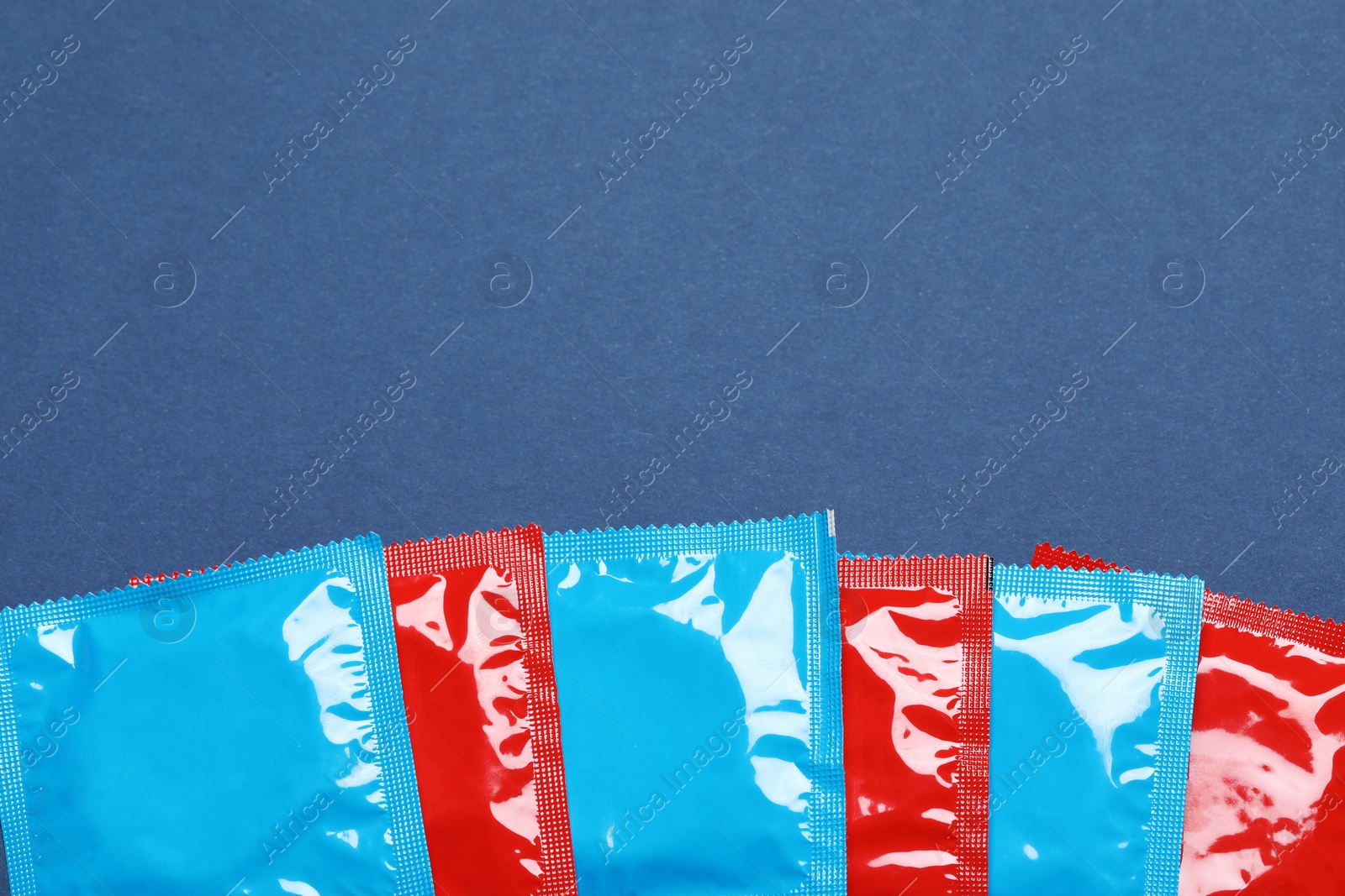 Photo of Condom packages on blue background, flat lay with space for text. Safe sex