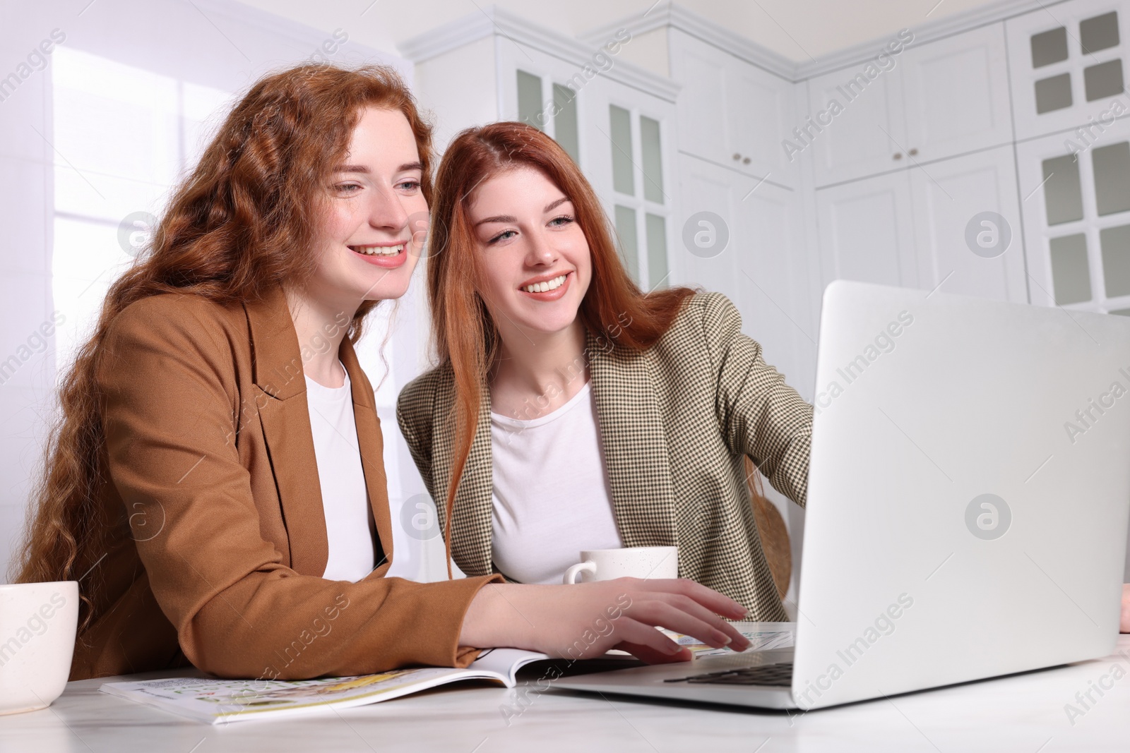 Photo of Beautiful young sisters spending time together in kitchen