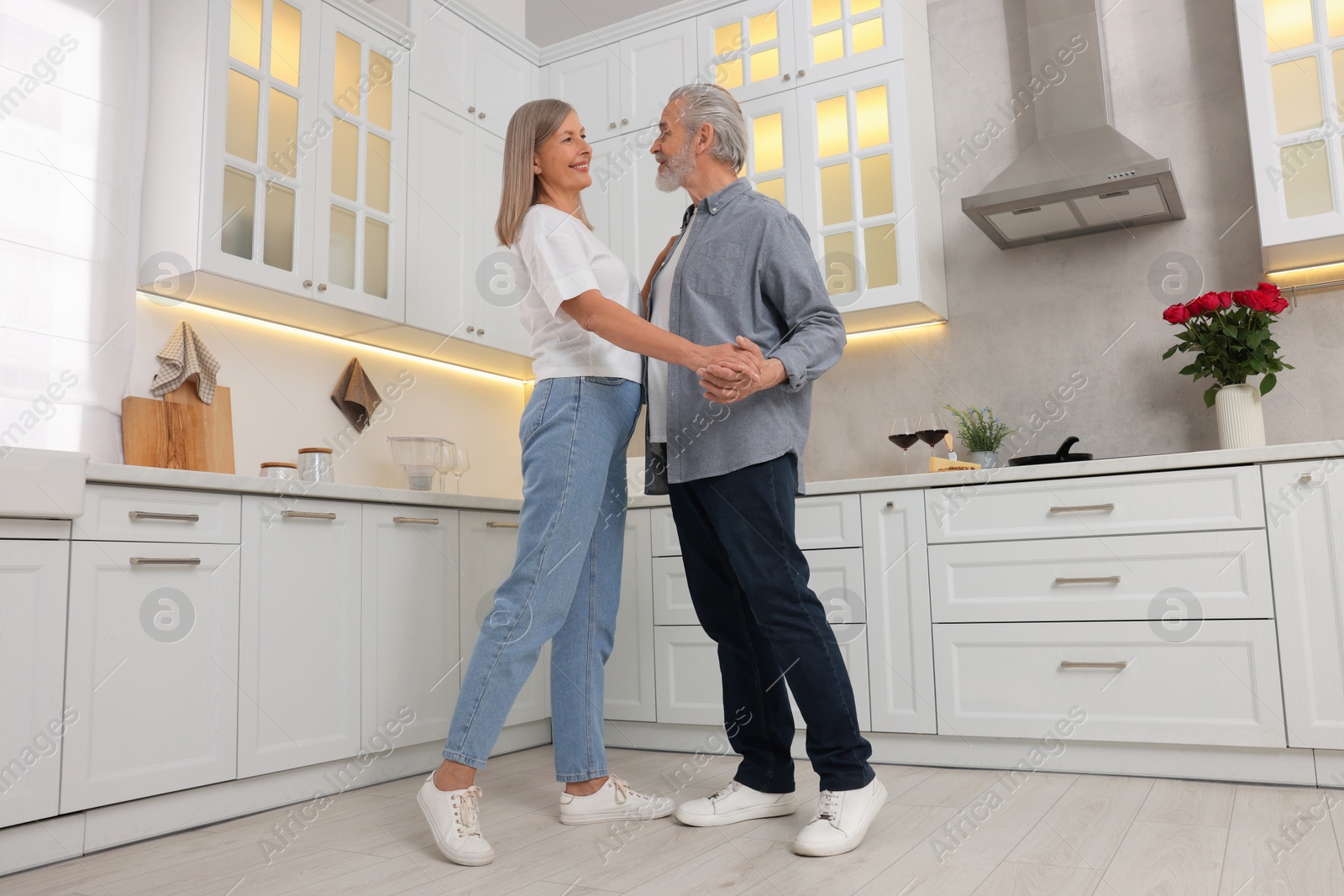 Photo of Happy affectionate senior couple dancing in kitchen, low angle view