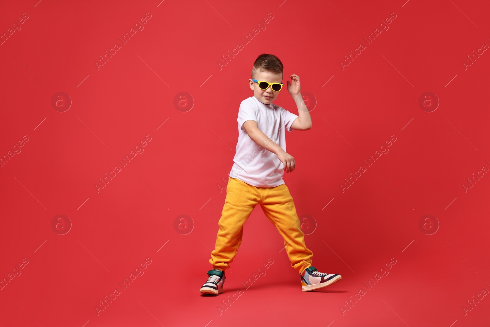 Photo of Happy little boy dancing on red background