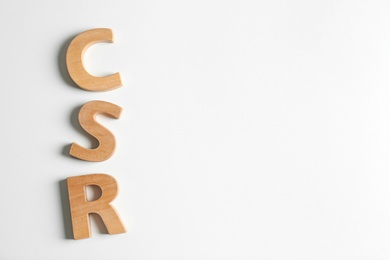 Photo of Wooden letters CSR on white background, top view. Corporate social responsibility concept