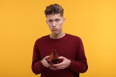 Photo of Upset man with empty wallet on yellow background