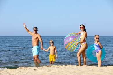 Happy family with inflatable ball and ring in sea. Summer holidays