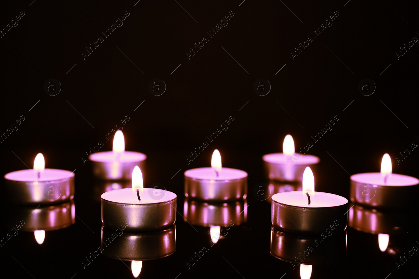 Image of Beautiful burning violet candles on black background. Funeral attributes