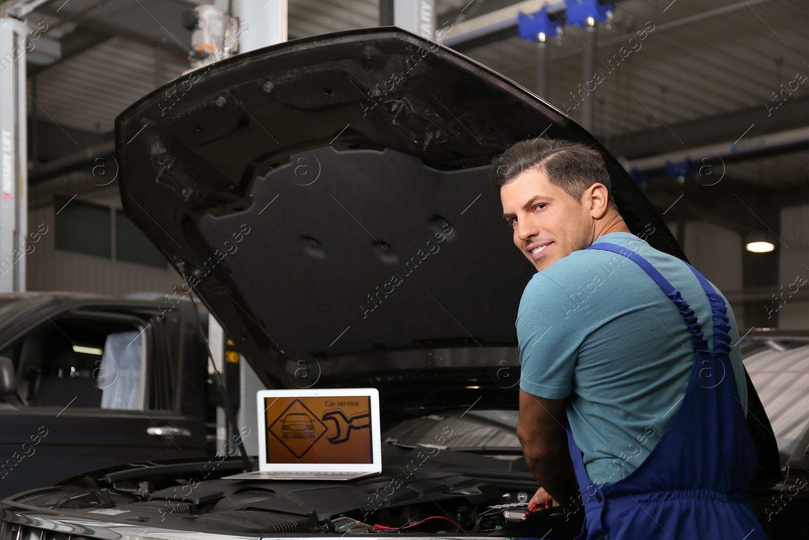 Photo of Mechanic with laptop doing car diagnostic at automobile repair shop