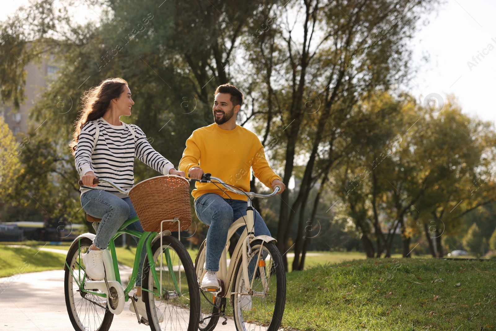 Photo of Beautiful couple riding bicycles in park, space for text