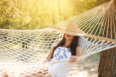 Young woman resting in comfortable hammock at green garden