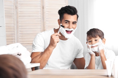 Father and son having fun while shaving in bathroom