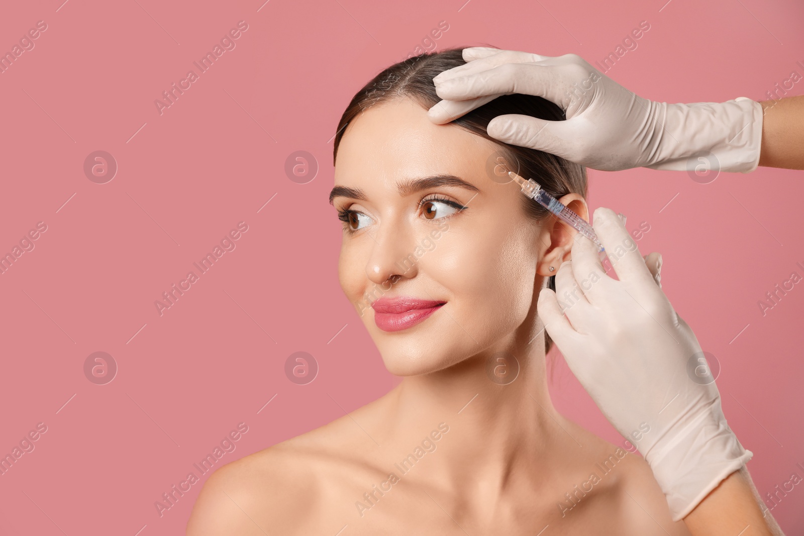 Photo of Beautiful woman getting facial injection on pink background. Cosmetic surgery