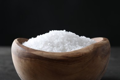 Photo of Natural salt in wooden bowl on table, closeup