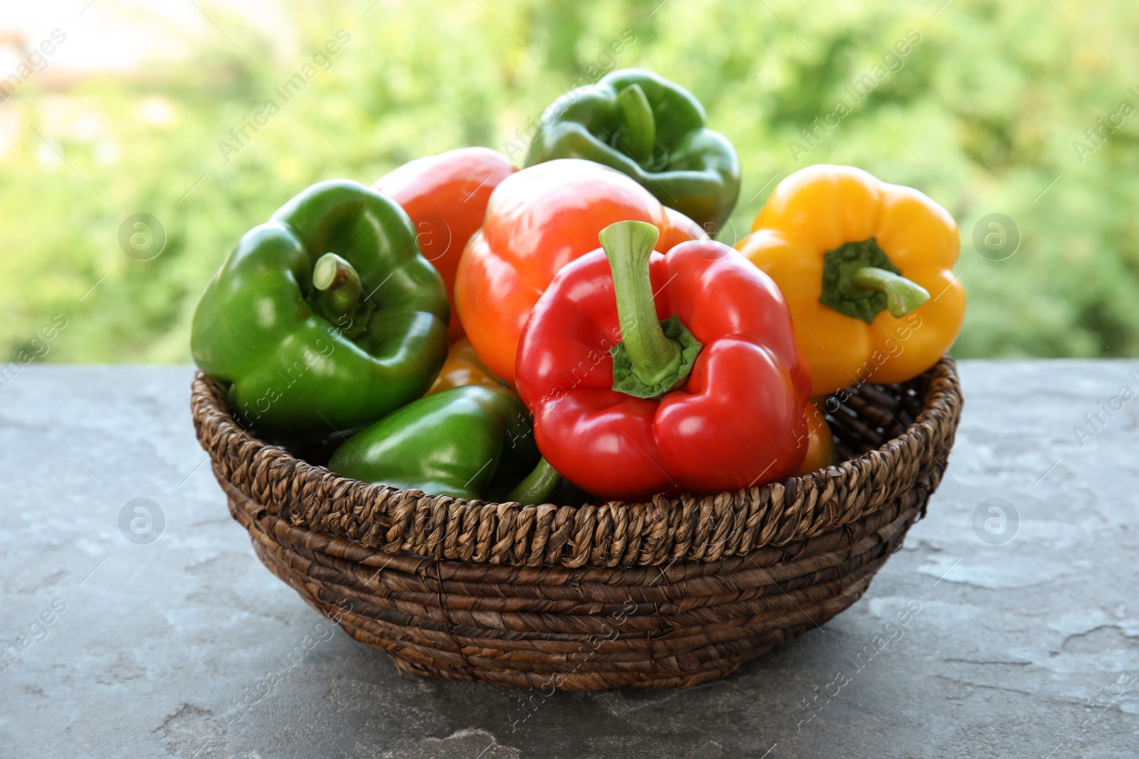 Photo of Bowl with ripe paprika peppers on table against blurred background