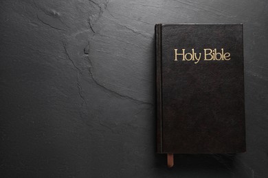 Photo of Hardcover Bible on black table, top view with space for text. Religious book