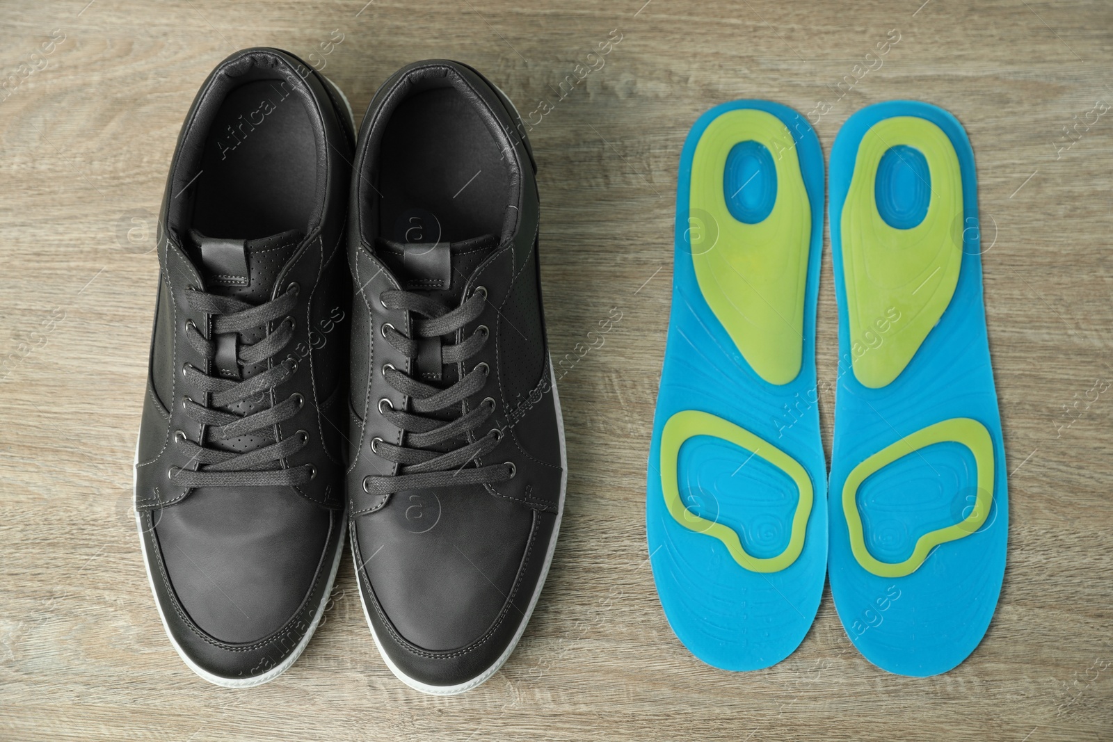 Photo of Orthopedic insoles near shoes on floor, flat lay