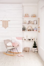 Stylish room interior with rocking chair, wall shelves and beautiful Christmas decor