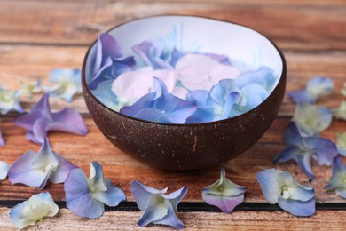 Photo of Spa composition. Aromatic water in bowl and flowers on wooden table, closeup