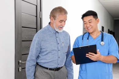 Doctor with clipboard consulting senior patient in clinic