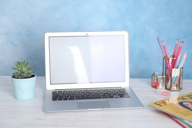 Photo of Modern laptop and stationery on white wooden table. Space for text
