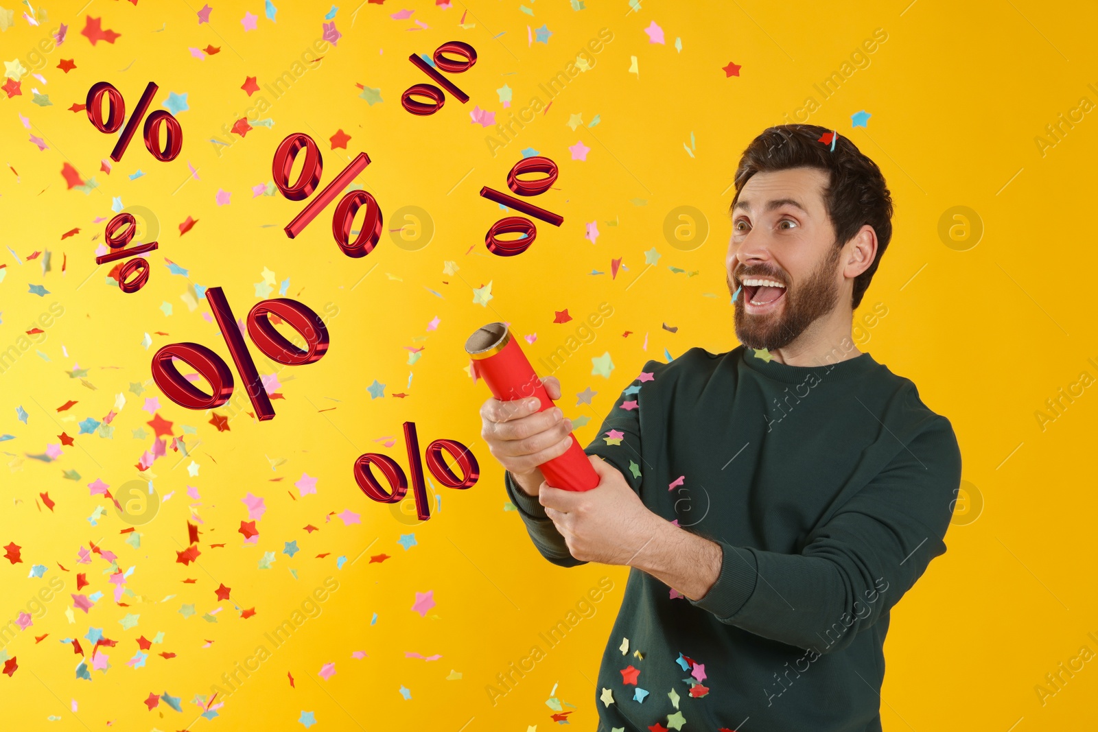 Image of Discount offer. Happy man blowing up party popper on golden background. Confetti and percent signs in air