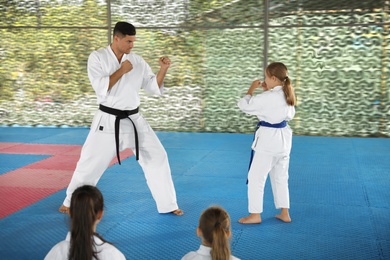 Photo of Girl practicing karate with coach on tatami outdoors