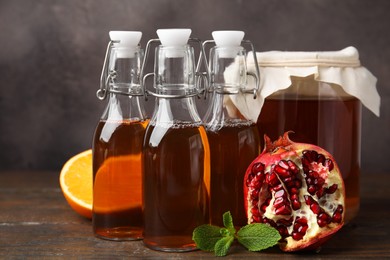 Photo of Tasty kombucha, mint and fresh fruits on wooden table